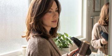 Butterfly cut brunette woman styling hair in mirror 2026